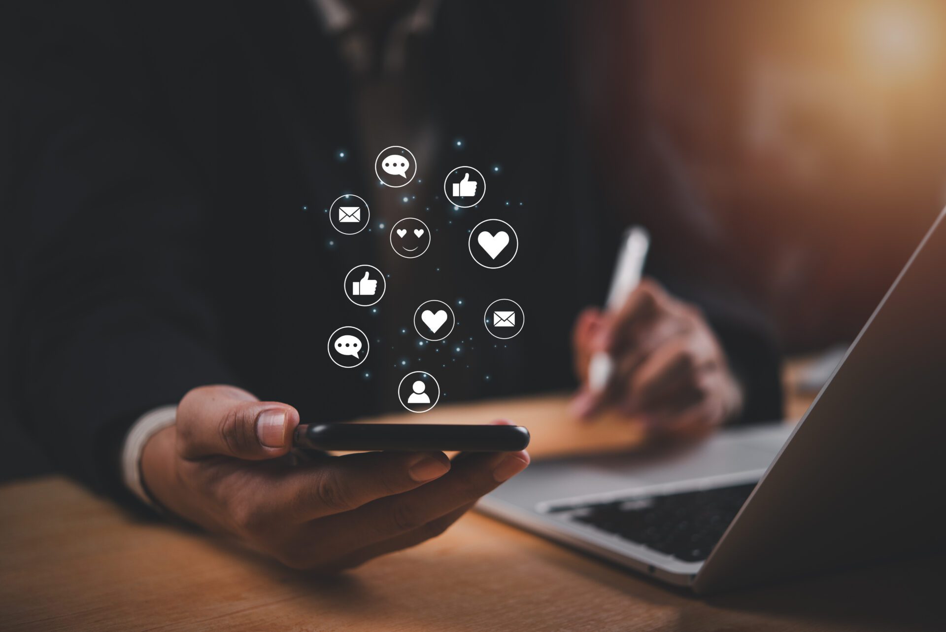 A businessman uses a smartphone with social media icons floating above it.